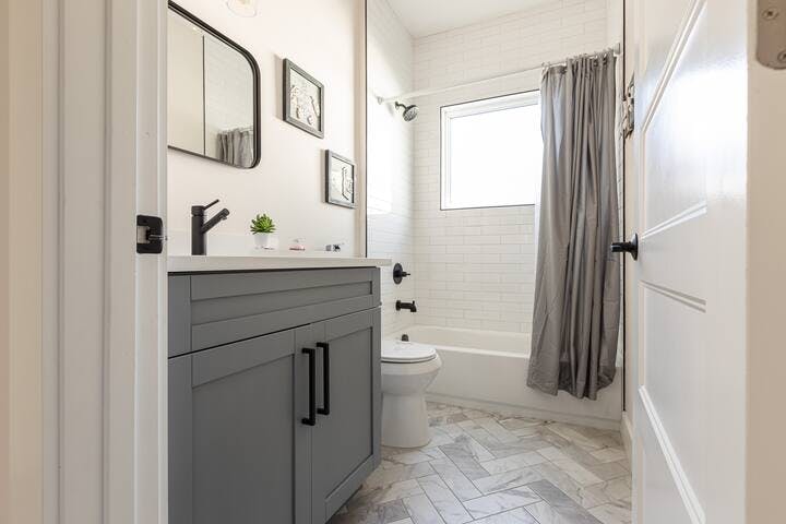 Bathroom 2: Discover convenience in our full-sized second bathroom, equipped with a tub and shower combo. Centrally located between two bedrooms and easily accessible from the living room. Book now for a comfortable stay! 