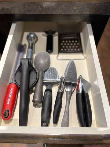 All sorts of kitchen gadgets, including a zester, juicer, garlic press, and an ice cream scoop.