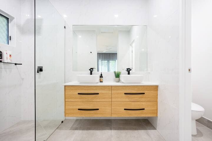 Our bathrooms are beautifully designed, featuring floor-to-ceiling tiling, rain showerheads and supplied with shampoo, conditioner and body wash. This ensuite has an adjoining private toilet.