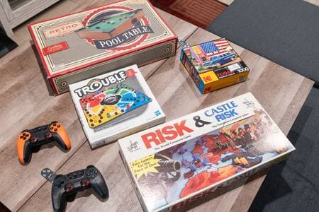 Living Room | Coffee Table + Games Coffee table raises to dining height and folds out. Board games: Trouble, Risk, Castle Risk, puzzle, mini pool table. Unpictured: Operation and Chess. Wireless controllers for retro console connect to projector.