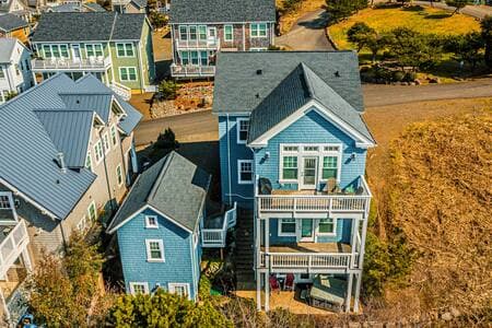The back of the house, which faces the ocean. Photo shows two decks and a hot tub patio. ADU on the left has game room above and queen bed/bath on lower floor.